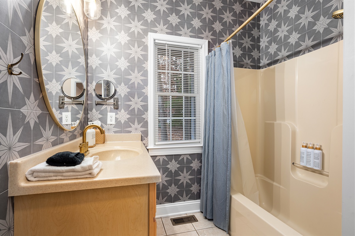 Bright full bath with playful patterned wallpaper — stocked with the essentials so you can pack light