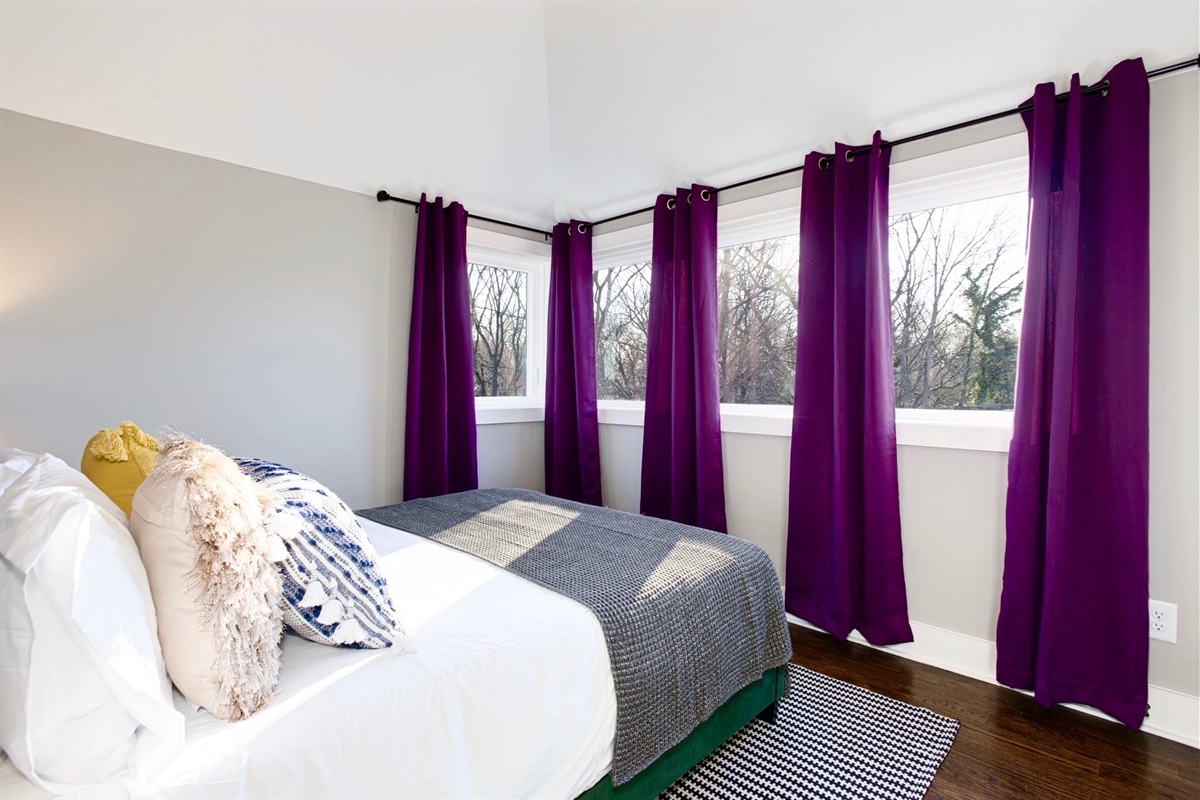 - Wake up to tree lined views & bold purple drapes that frame the sunlight perfectly - Soft pillows, clean lines, & a comfy bed make this space equal parts stylish & soothing - Whether it’s morning light or afternoon naps, this corner is built for calm