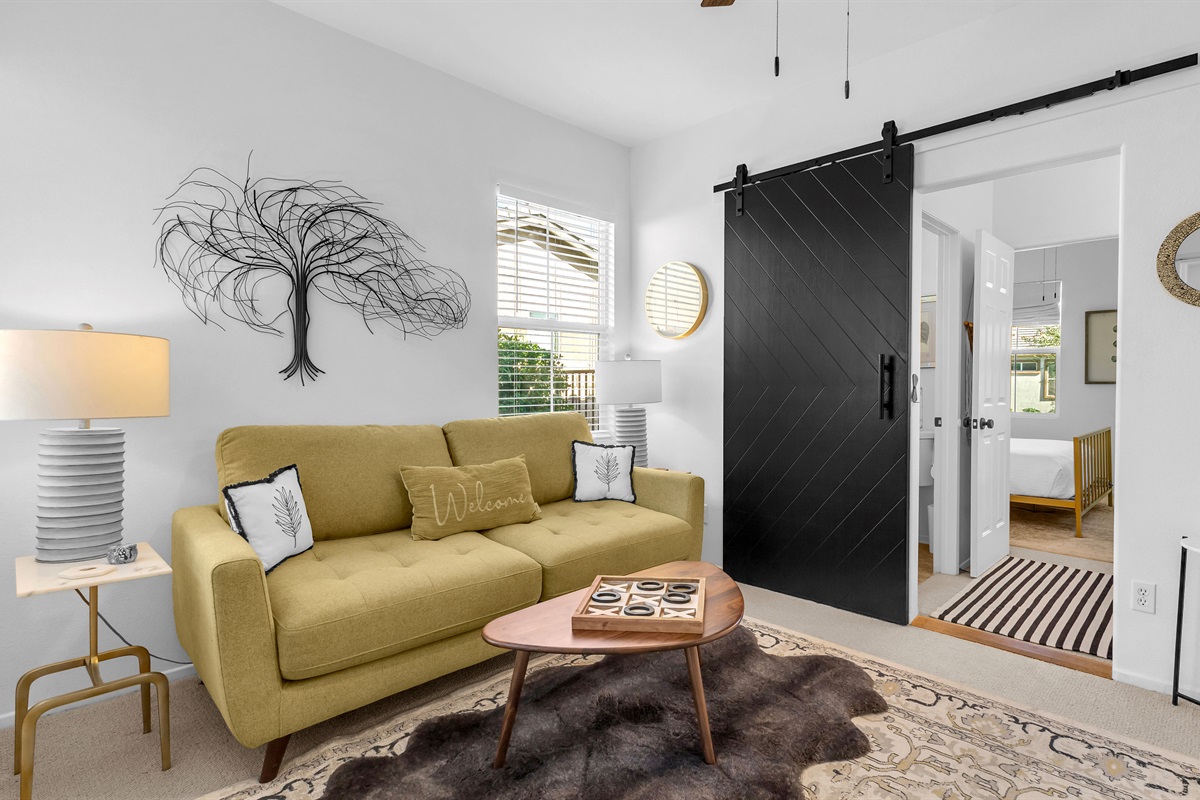 🛋️ Den/Bonus Room  Relax in this stylish sitting area with a comfy sofa, warm lighting, and a sleek barn door leading to the ensuite bedroom—ideal for reading, games, or quiet moments.