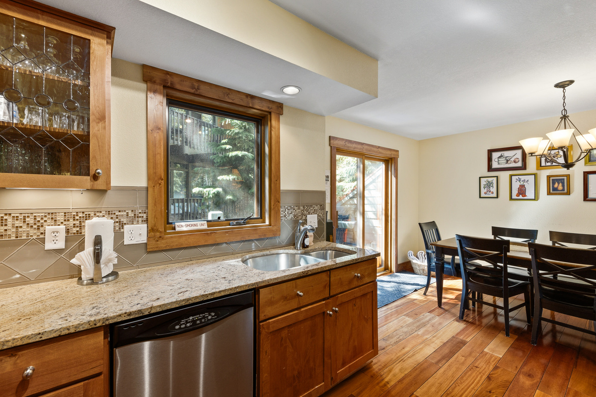 Kitchen with wood and hot tub view, balcony with hot tub and gas grill, and ample dining space. 