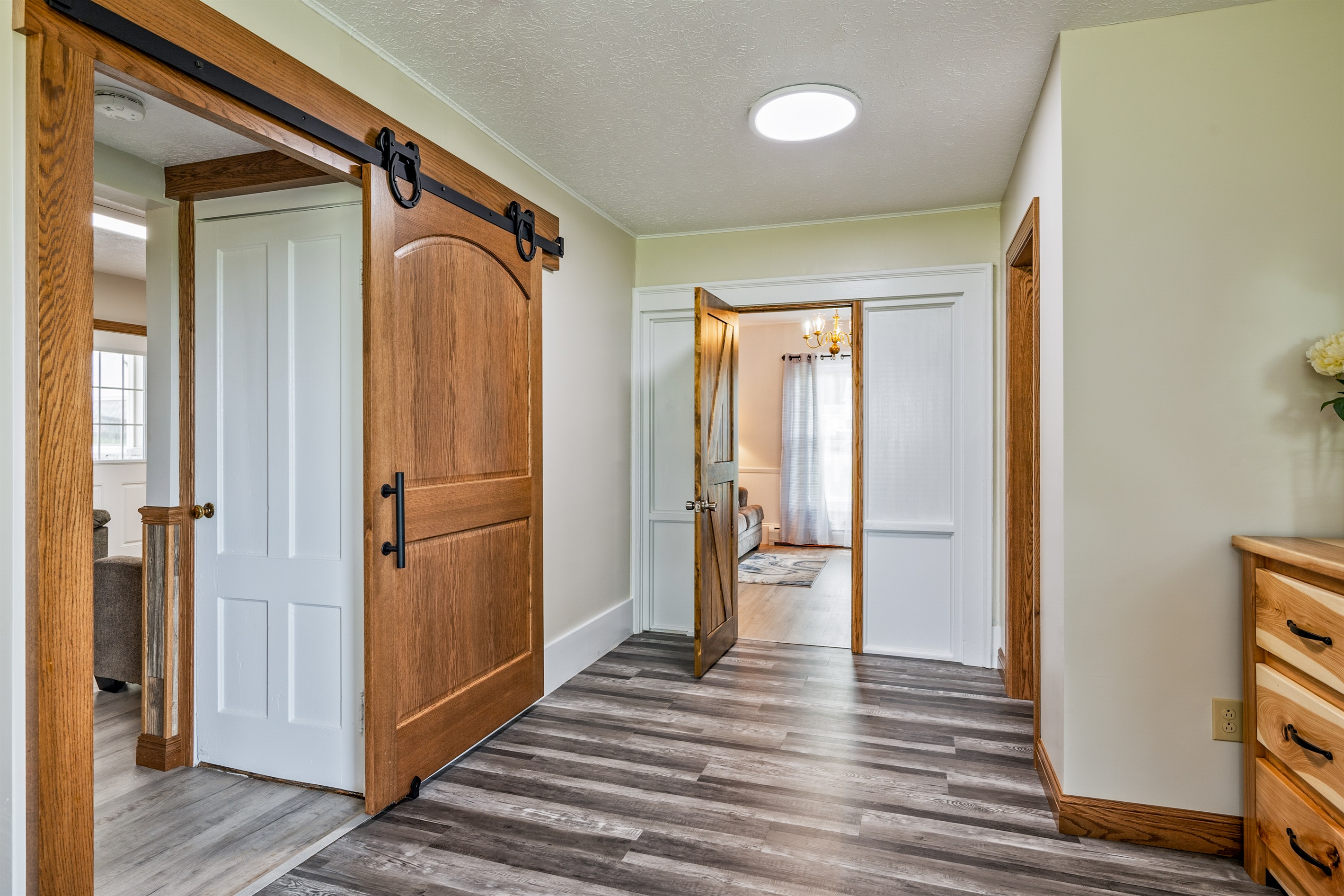 Inviting hallway with warm wood finishes and direct views into a cozy, light-filled sitting room.