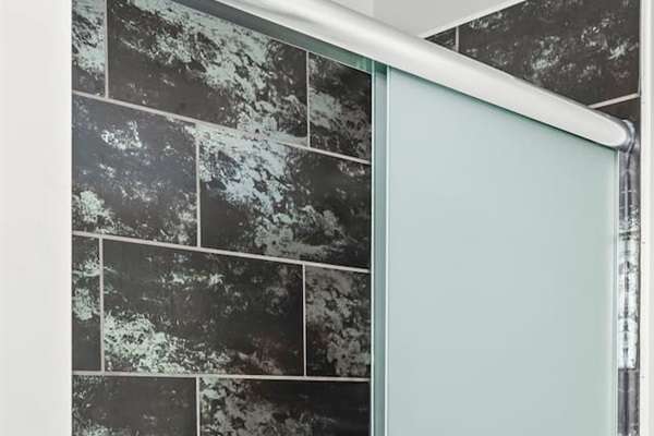 Walk-in shower with frosted glass door, stylish tile surround, and modern fixtures.