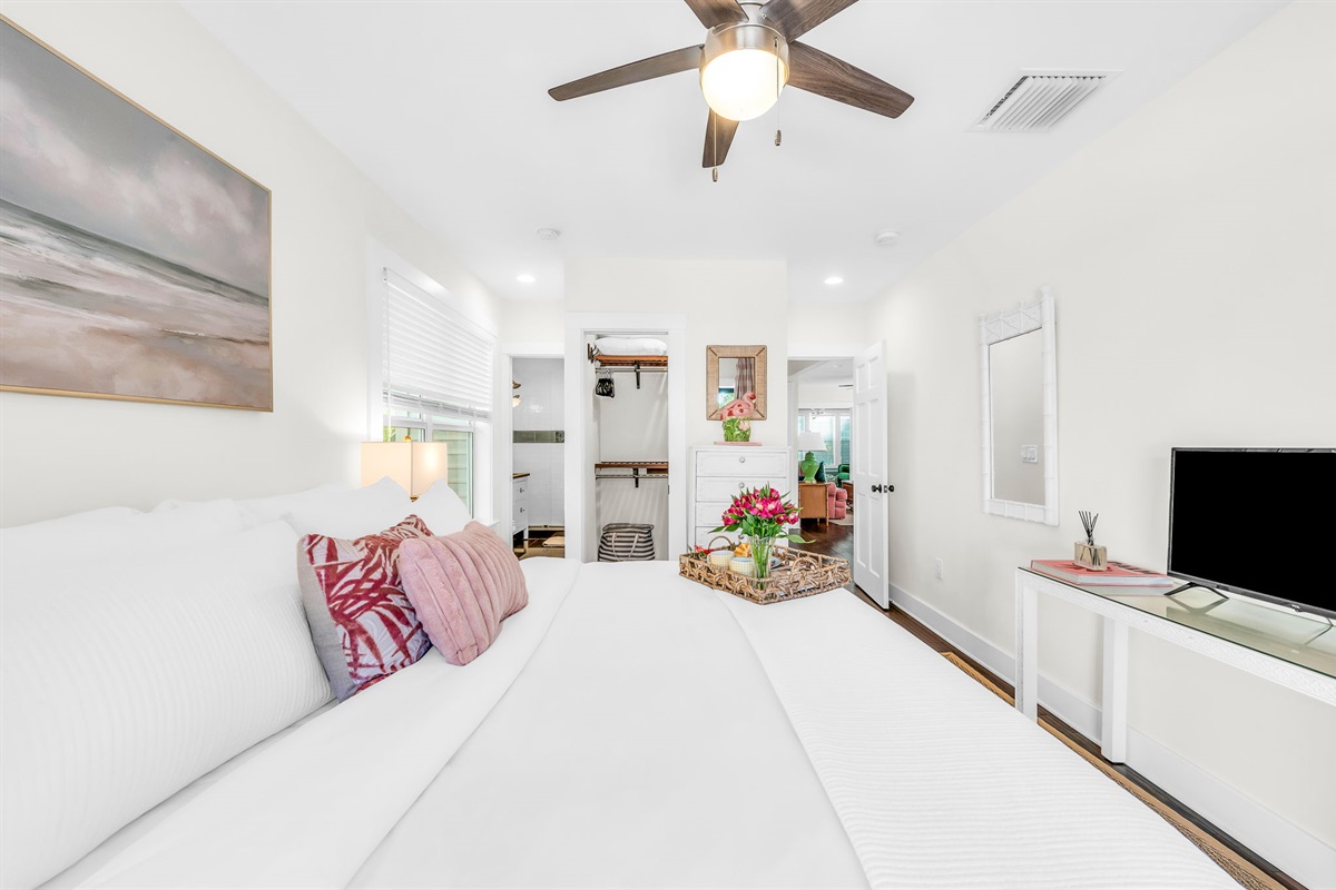 Serene king primary suite featuring a smart TV, private en-suite bathroom, and elegant French doors that open directly to the pool—perfect for seamless indoor-outdoor living and relaxing mornings or evenings.
