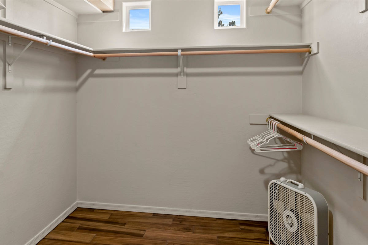 Explore the spacious walk-in closet, complete with hangers and extra storage, featuring a box fan for your convenience.