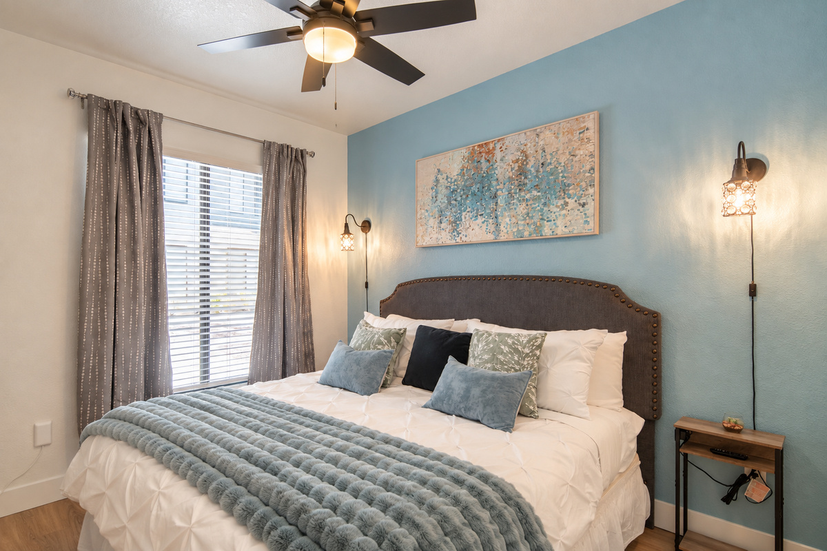 A stylish bedroom with cozy bedding and a bold accent wall 🎄✨ Wake refreshed with bright natural light and enjoy peaceful mornings on your private patio.