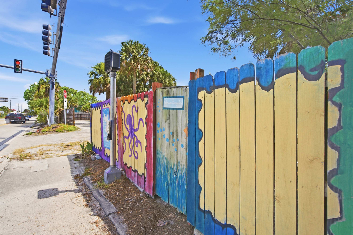 The mural runs the entire length of the fence in yellows and violets, a genuine piece of Vilano Beach folk art. Guests photograph it constantly, which tells you most of what you need to know about the street.
