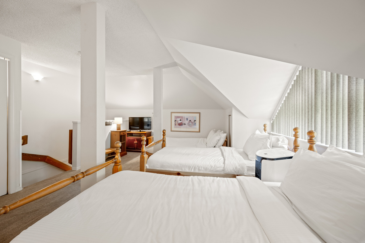 The loft bedroom sleeps 5, with a double bed in front and three twins beyond. It has no door and no sightlines from below.