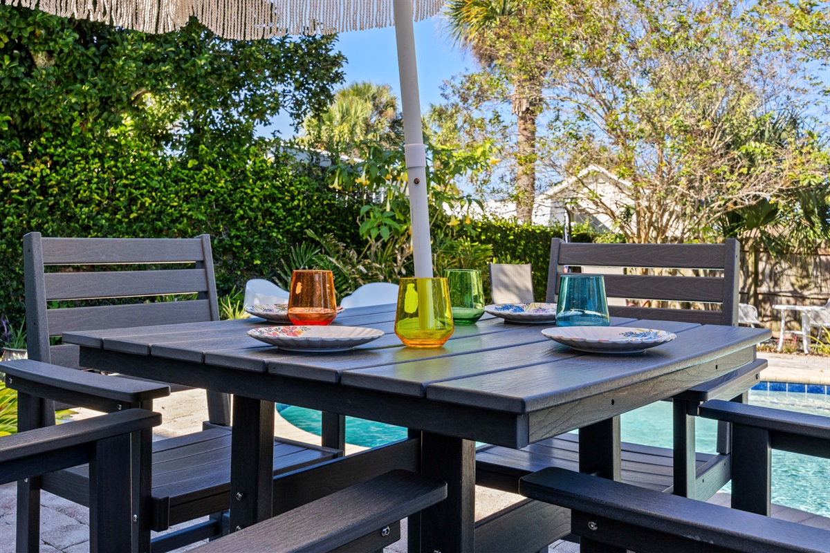 Colorful Poolside Dining Setup
A stylish outdoor dining table set with vibrant glassware and a fringed umbrella. Overlooking the pool and tropical landscaping, it’s perfect for alfresco meals.
