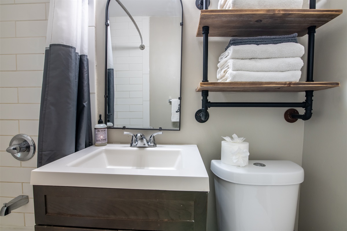 Compact yet stylish bathroom featuring open shelving and fresh towels.