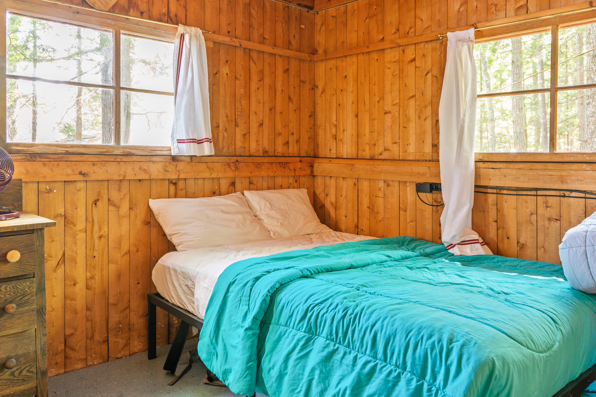 Guest bedroom with dock views at Loonrise Point! Full-size bed framed by dual windows, with the left window looking directly out at the dock. Enjoy full privacy walls & tranquil lake surroundings on Beech Hill Pond in Otis, ME.