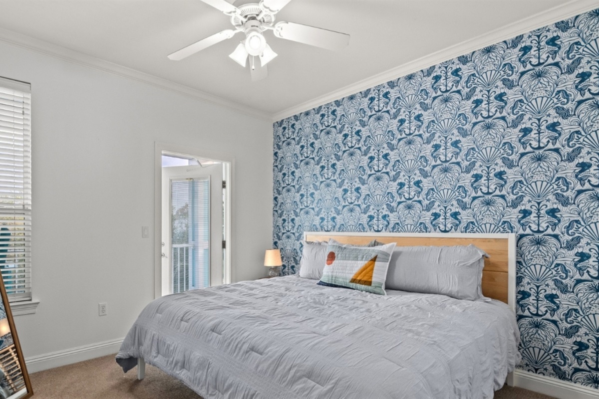A king bed and whimsical seahorse wallpaper that says you're at the beach.