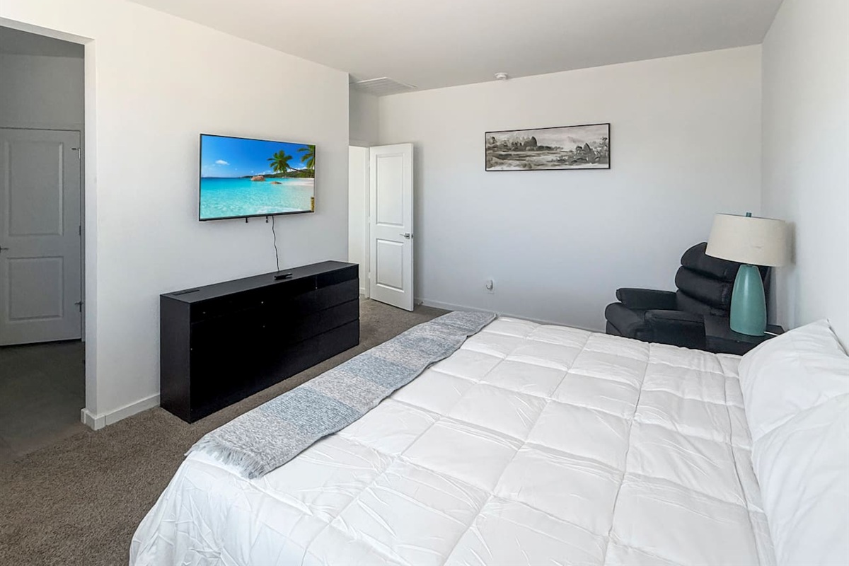 Bedroom with bed, TV, dresser, chair, and lamp