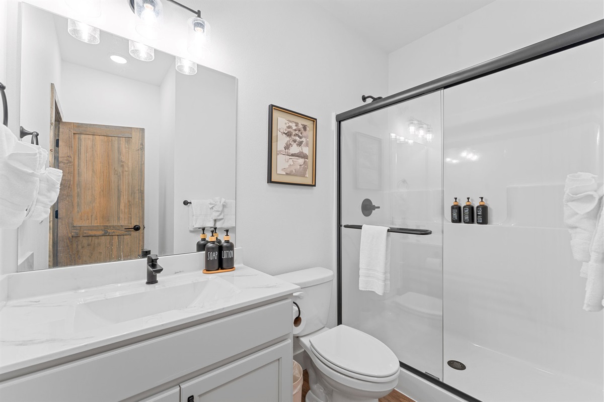 Attached ensuite bathroom with clean, modern amenities and a glass-enclosed shower and fresh linens.