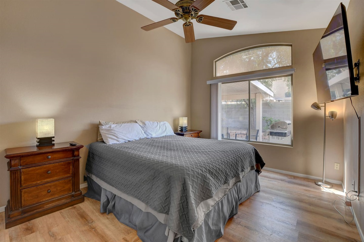 Bright bedroom with TV, ceiling fan, hardwood floors & patio view