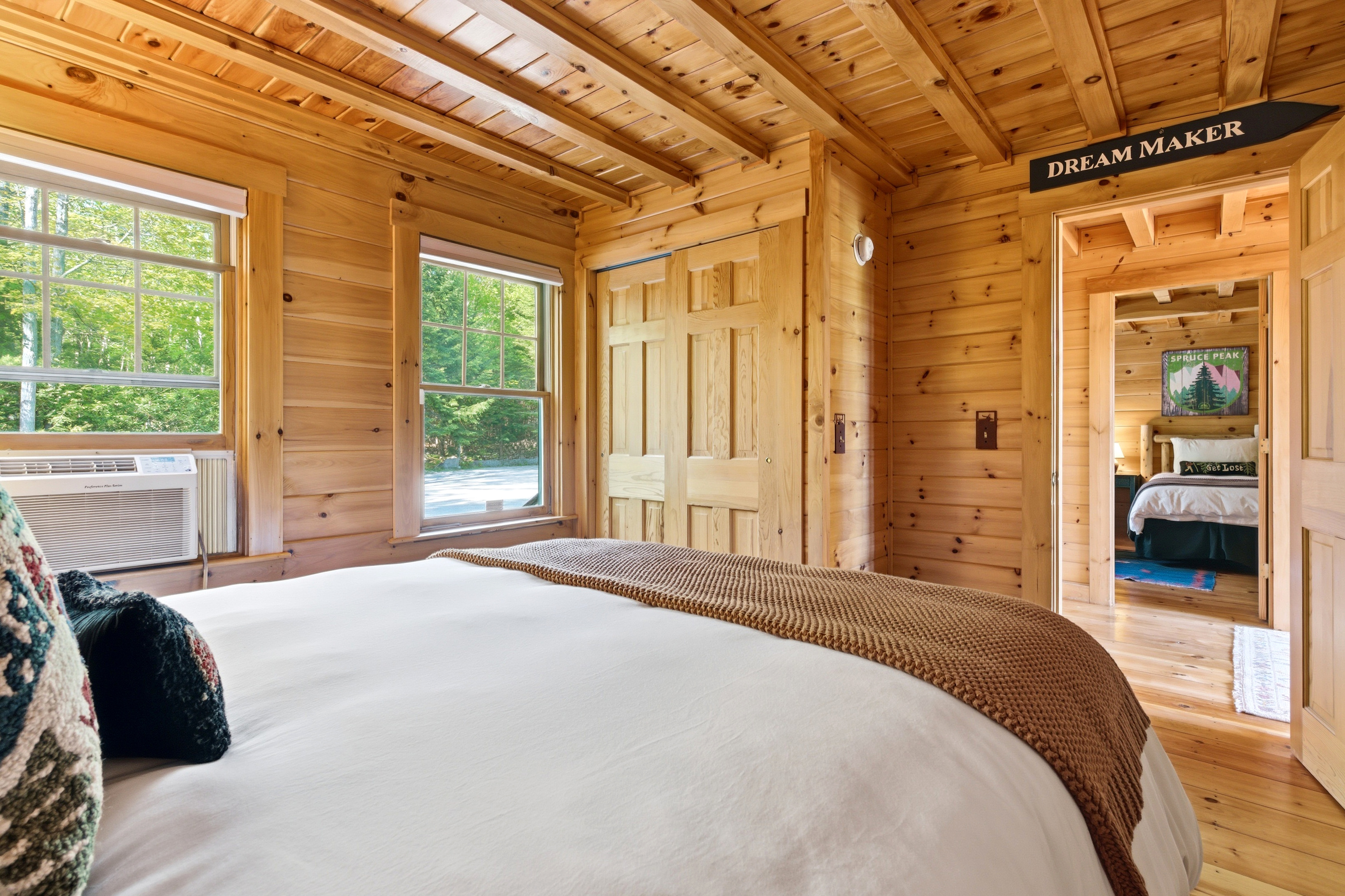 Retreat to a cozy wood-lined bedroom featuring warm cabin charm and peaceful forest views.