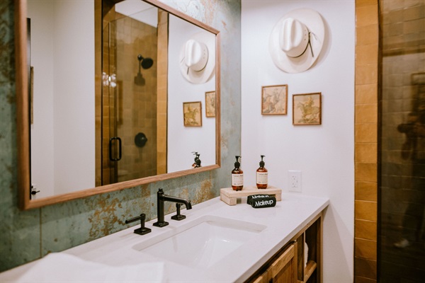 Walk-in tile shower and designer vanity in the Corral Suite's private en-suite bath &mdash; modern Western finishes at Gaines Ranch on the Square.