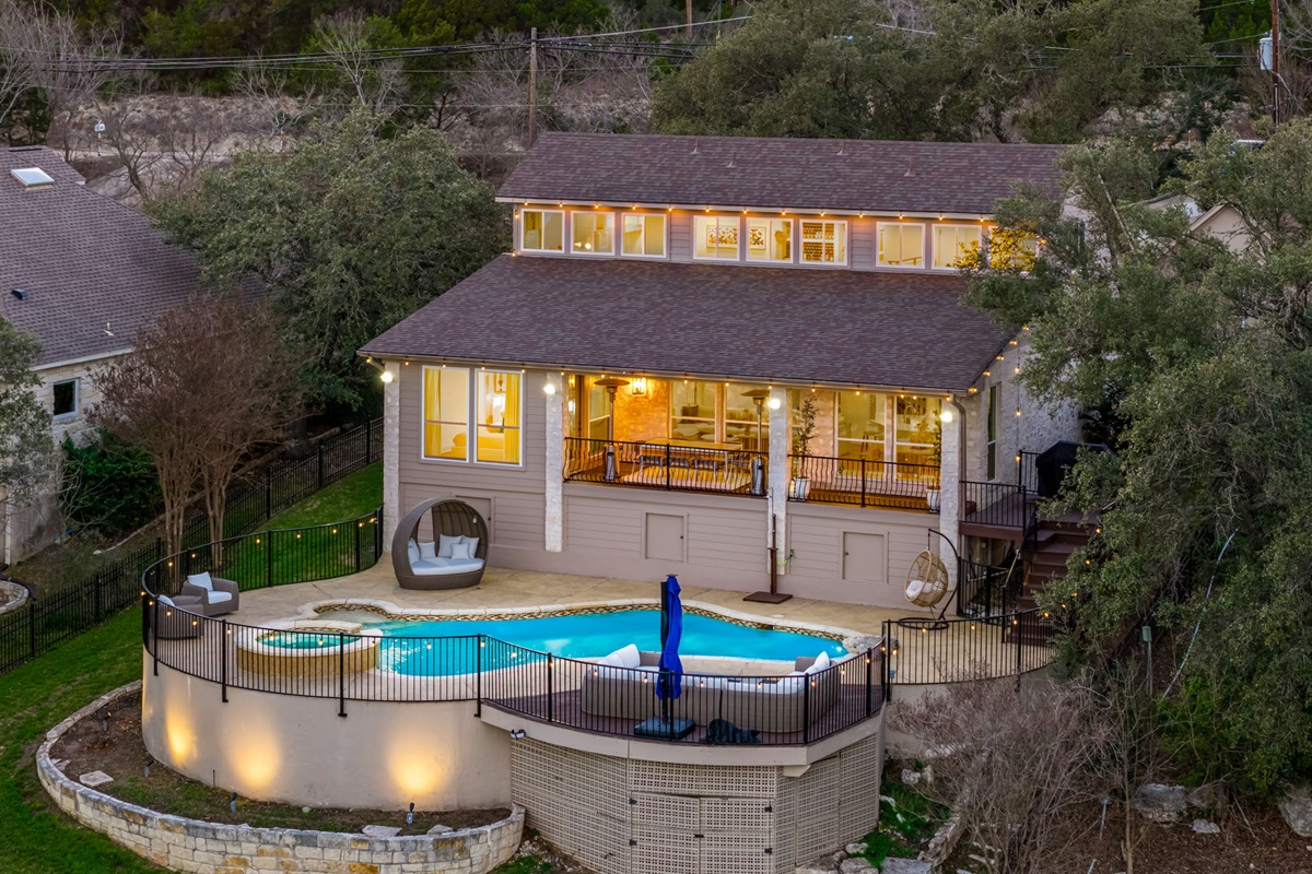 Beautiful evening view of the home with glowing backyard pool and spa.