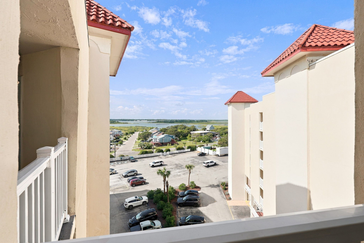 Balcony overview showing the resort grounds, parking area, and surrounding architecture.