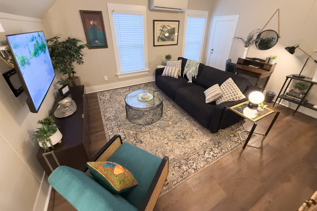 Living room with SmartTV, queen sofabed, desk, and games.