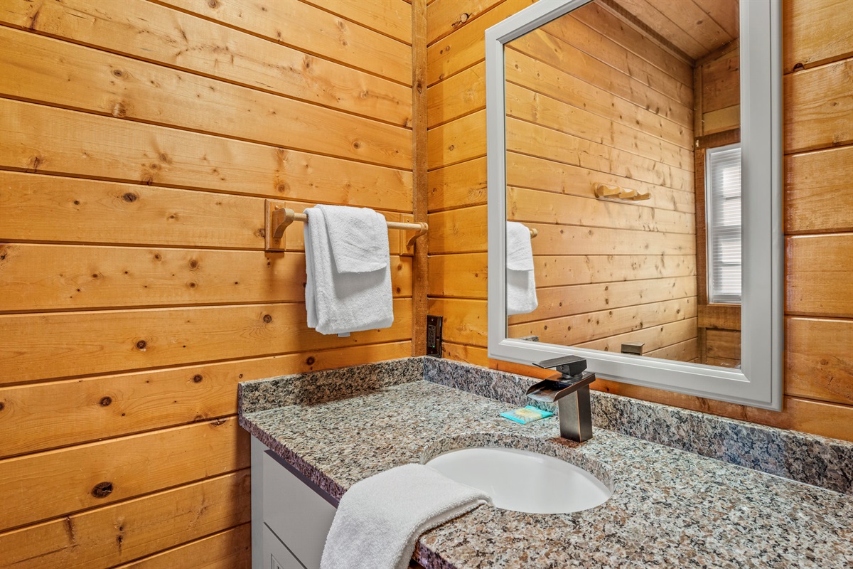 Bright bathroom vanity with wood walls and fresh towels.