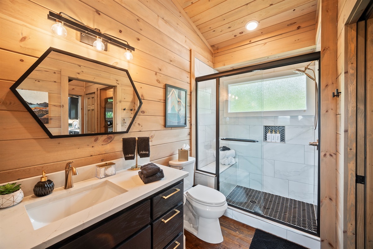 Bathroom-two features a walk-in shower with modern black and gold accents. Chic, functional, and effortlessly stylish.
