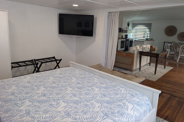 View from the upstairs king bed at Villa Coral looking past a large wall-mounted flat screen television into an adjacent open-concept second living room lounge and kitchenette area in Dorado, Puerto Rico.
