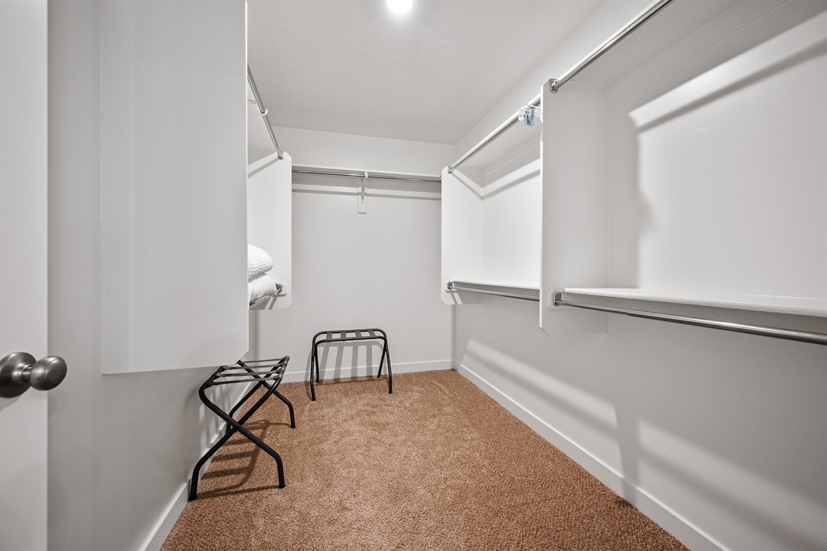 This well-lit walk-in closet includes luggage racks and plenty of space to store clothes, shoes, and travel essentials.
