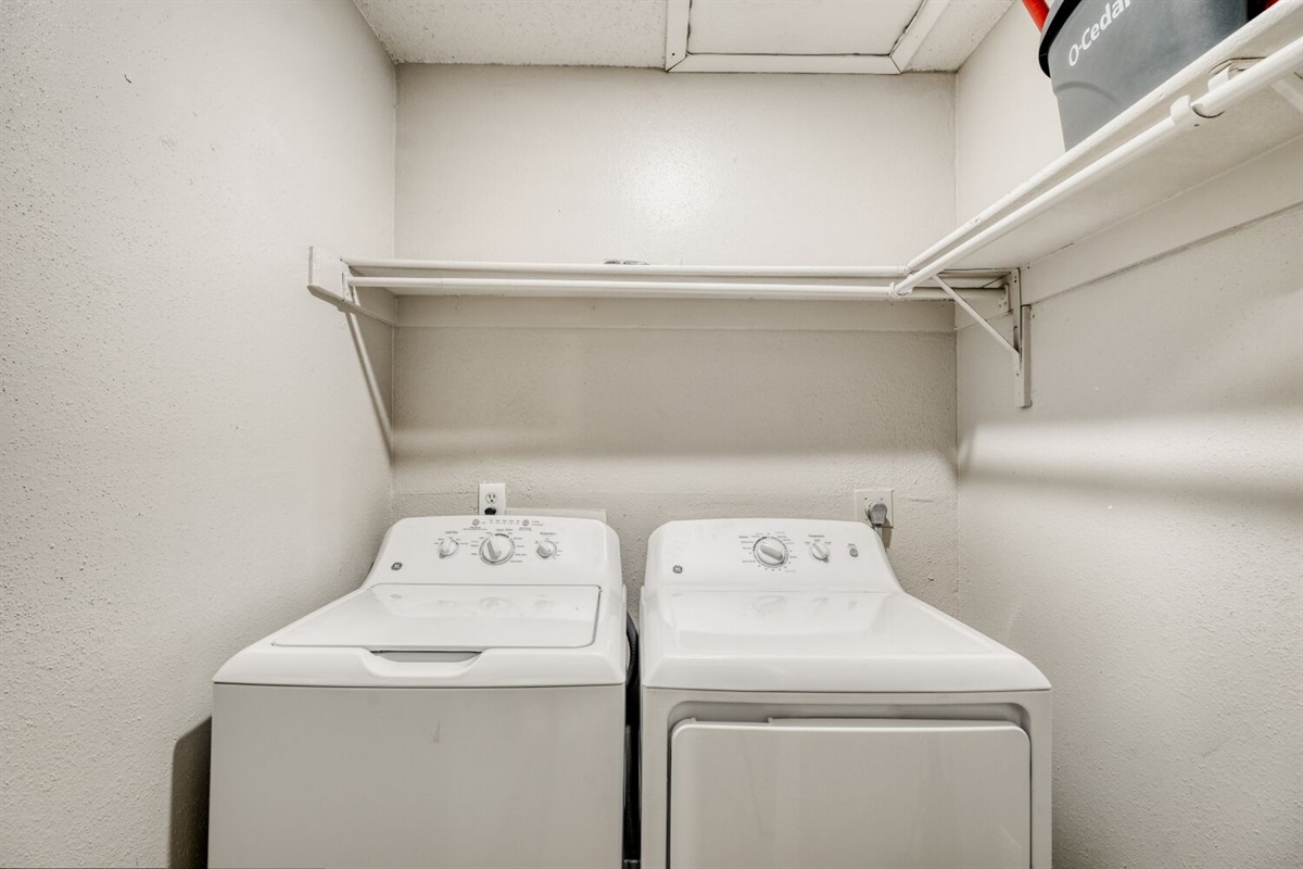Compact laundry room with washer, dryer, and convenient overhead shelving.
