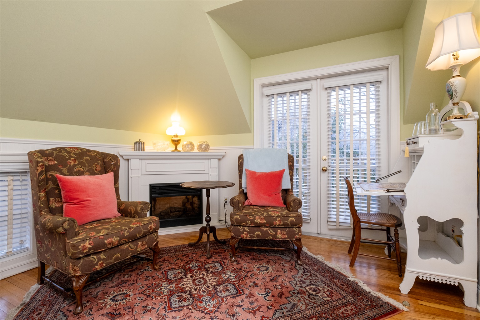 Cozy sitting area with upholstered chairs, writing desk, and French doors bringing in natural light.