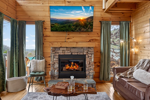 Stone fireplace, Smart TV, and a whiskey on the hearth — the main living room is the kind of place you sit down and suddenly it's midnight