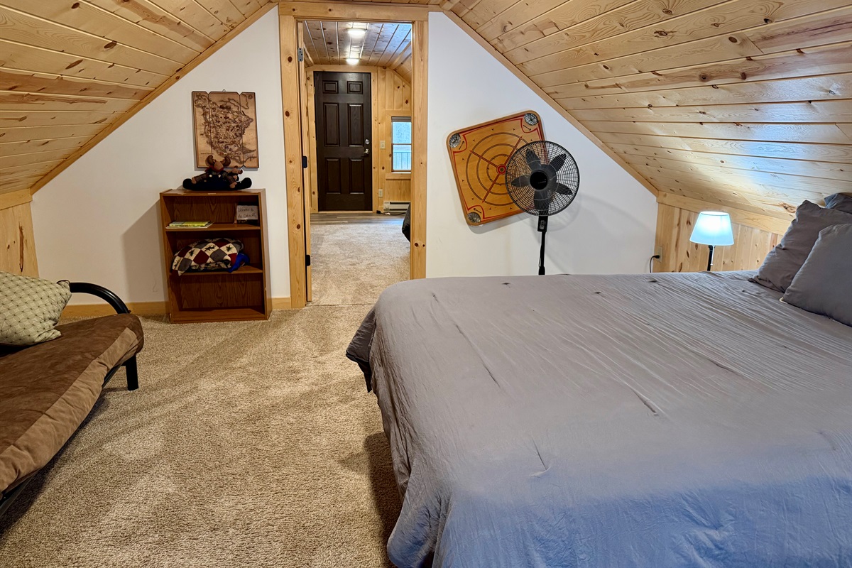 A cozy upstairs bedroom with a comfortable queen bed and a versatile futon-style loveseat that can sleep an additional guest. Warm, inviting, and thoughtfully designed for flexible sleeping arrangements.