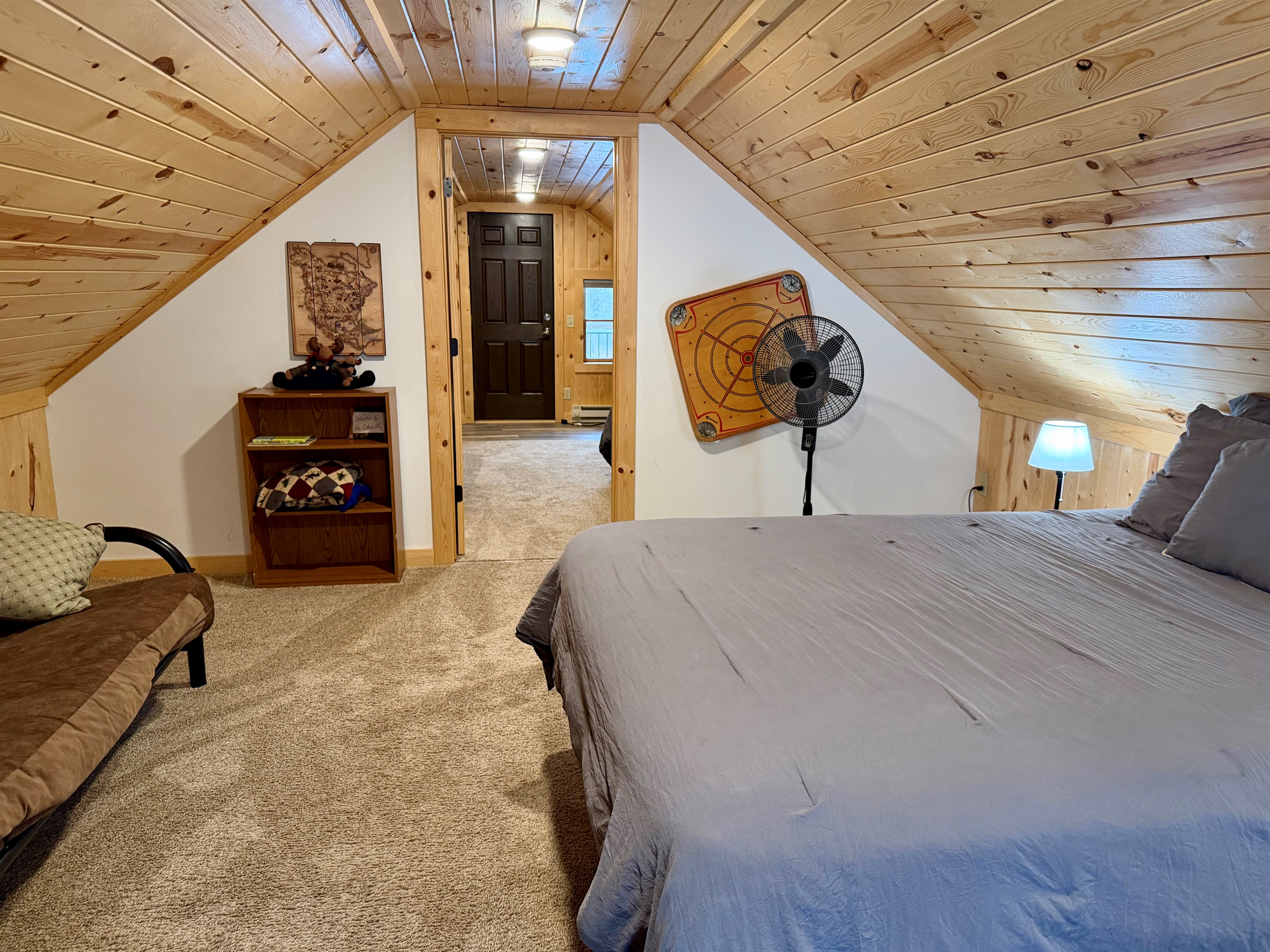 A cozy upstairs bedroom with a comfortable queen bed and a versatile futon-style loveseat that can sleep an additional guest. Warm, inviting, and thoughtfully designed for flexible sleeping arrangements.