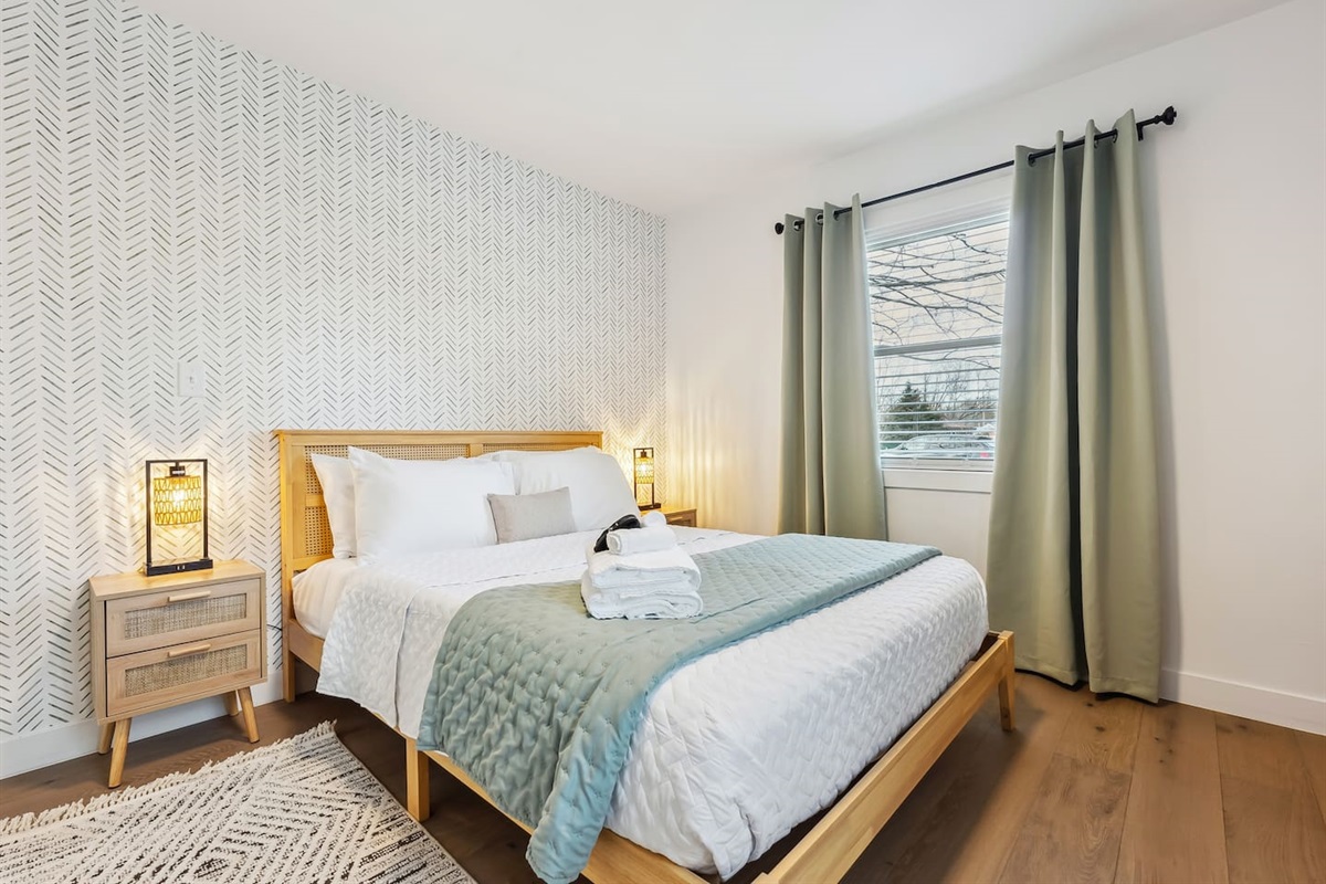 This modern room features a soft green spa color, a comfortable queen bed, and a 32-inch TV to enjoy while settling in for the night.