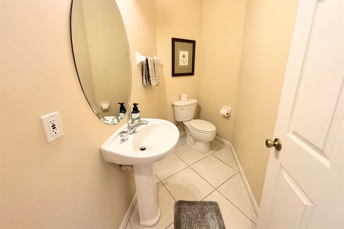 Convenient half bathroom with pedestal sink, tile flooring, and clean neutral finishes.