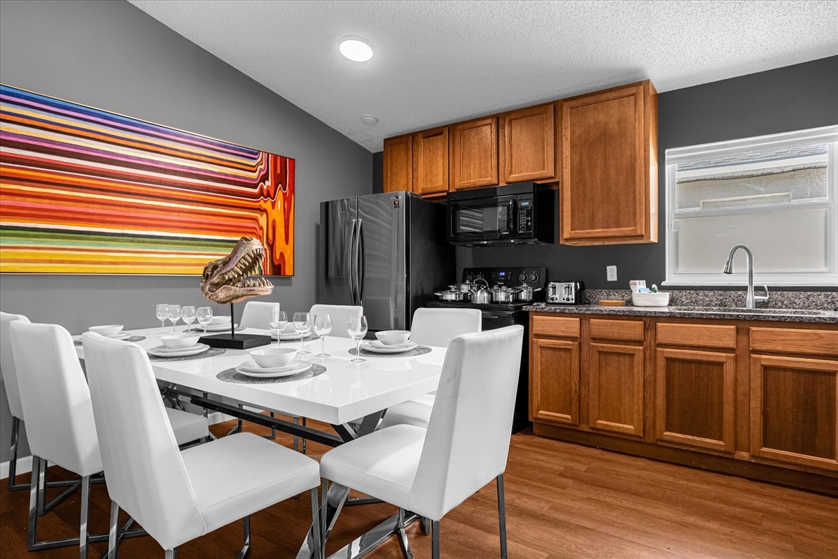 Modern kitchen and dining area with wooden cabinetry and a colorful wall art.