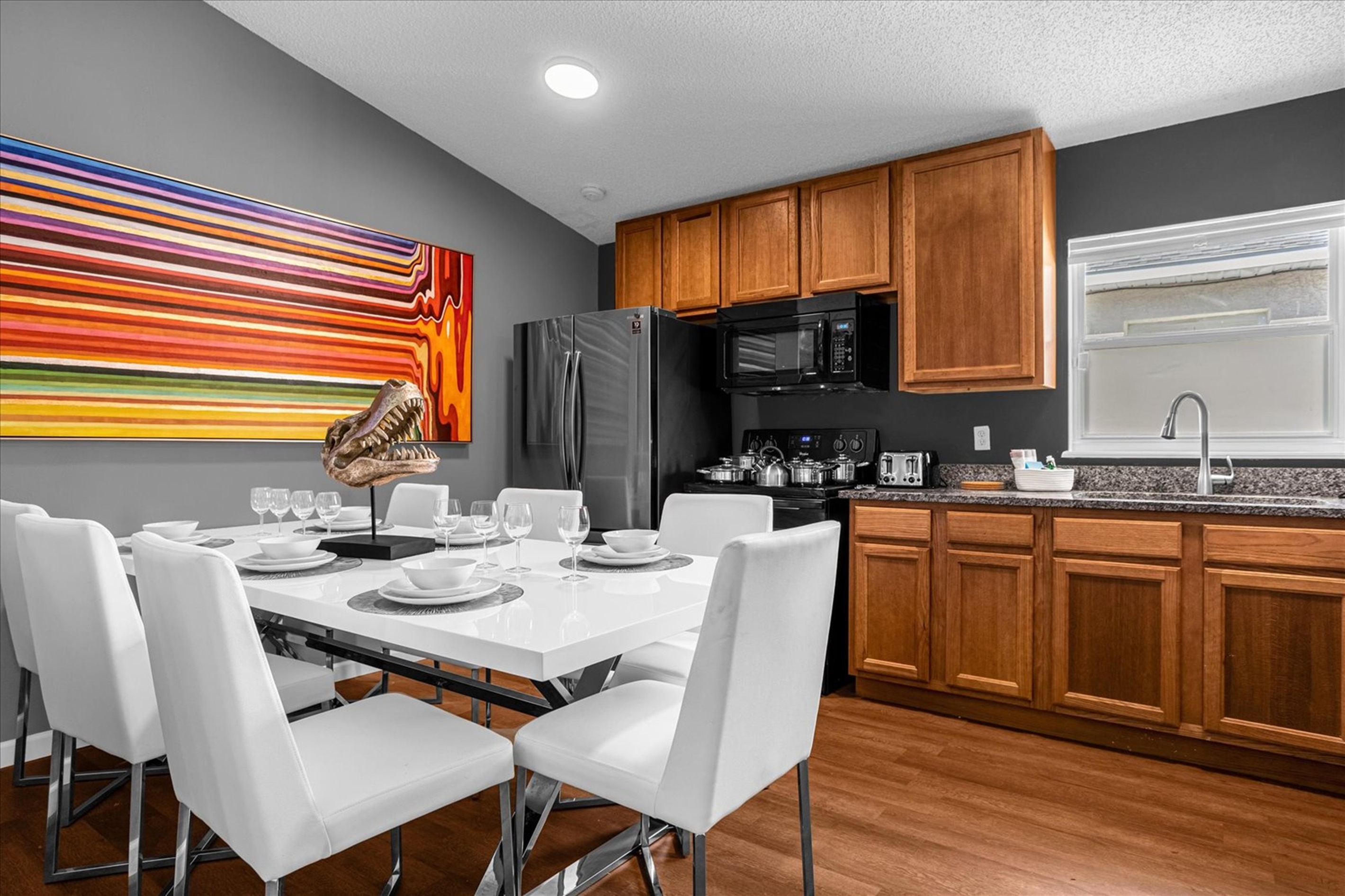 Modern kitchen and dining area with wooden cabinetry and a colorful wall art.