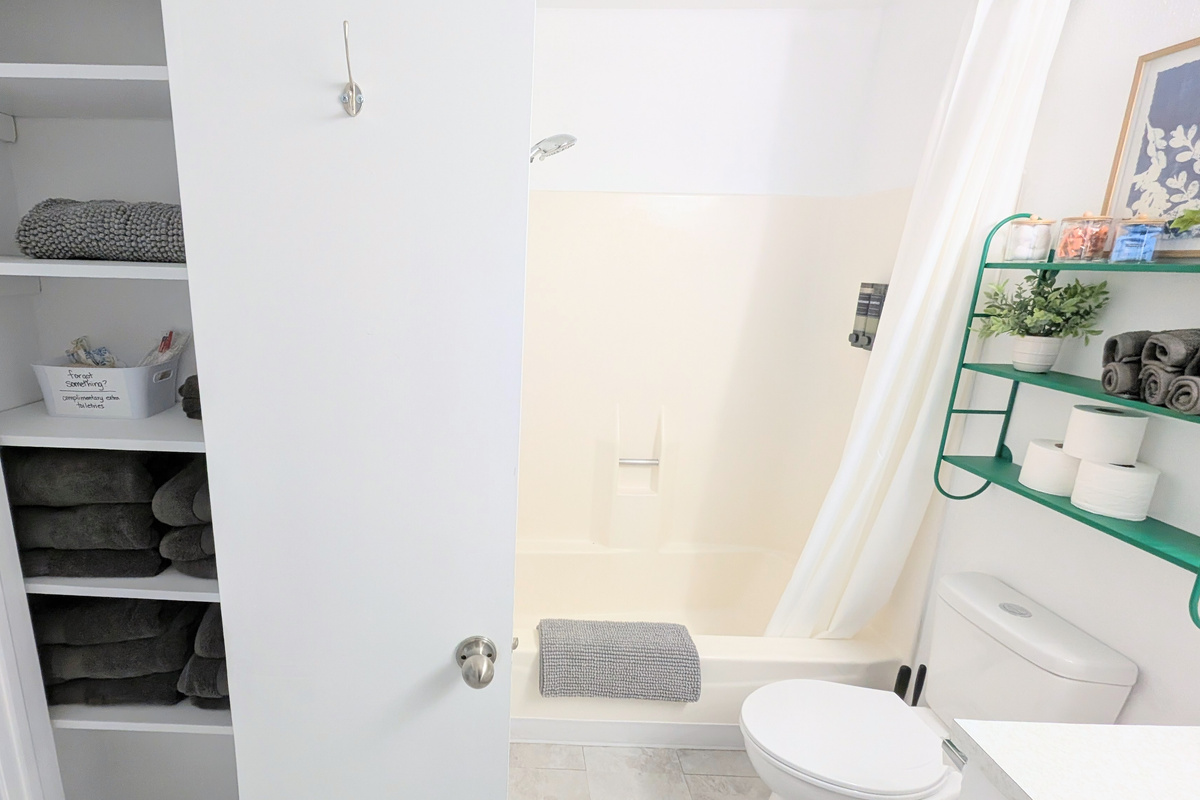 The bathroom features a fully supplied linen closet, along with extra hooks for conveniently hanging towels to dry.