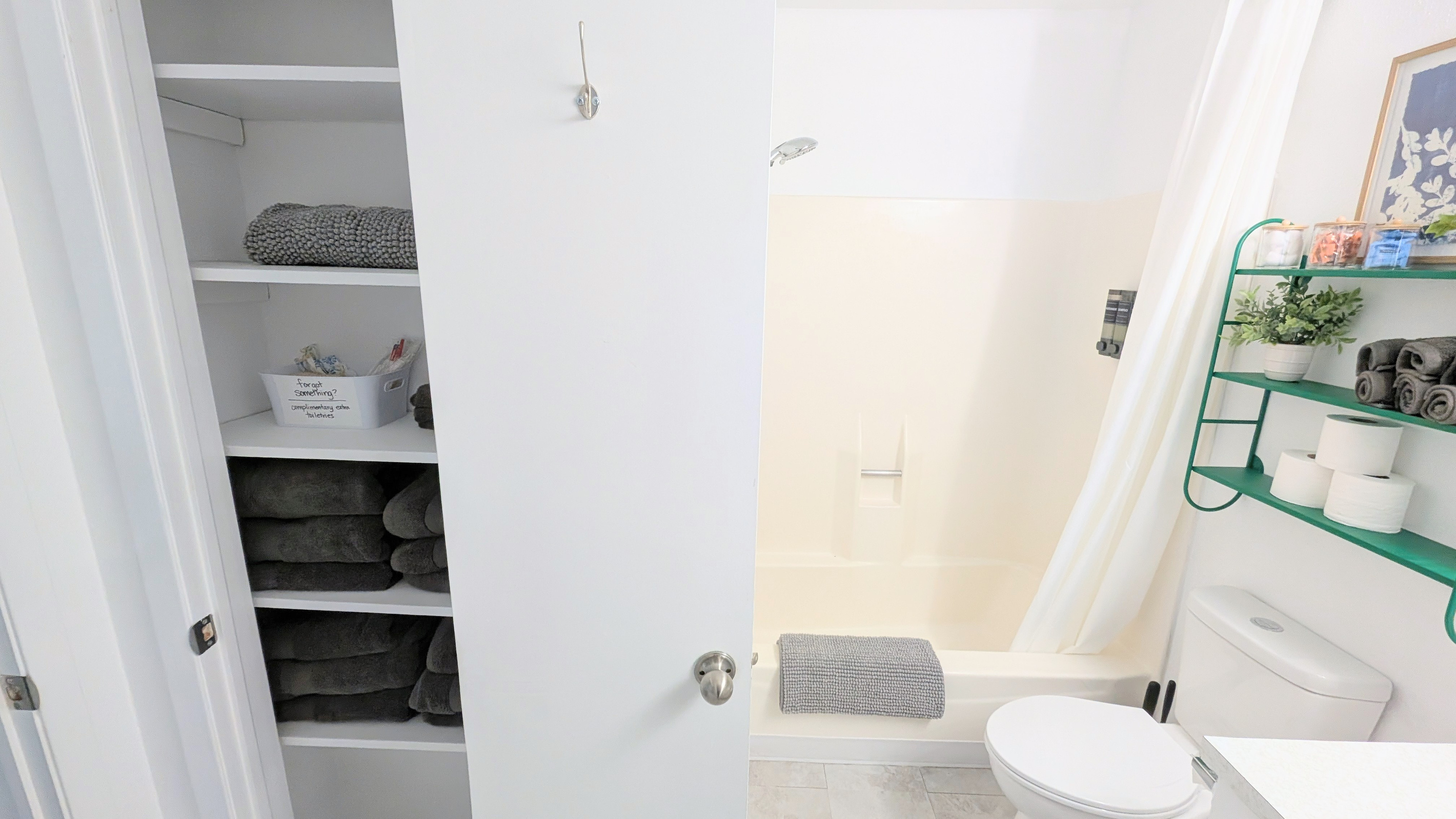 The bathroom features a fully supplied linen closet, along with extra hooks for conveniently hanging towels to dry.