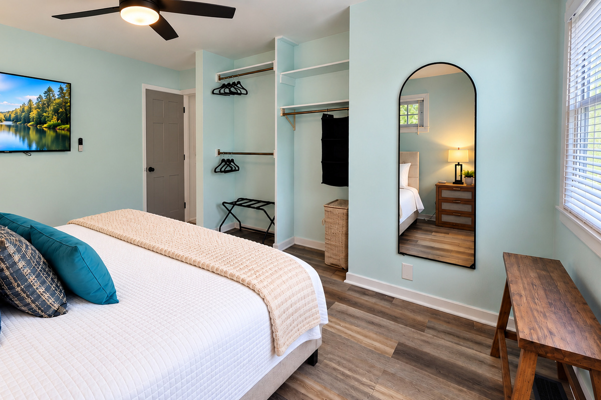 Spacious king bedroom with Smart TV, full-length mirror, open closets, luggage rack & bench.
