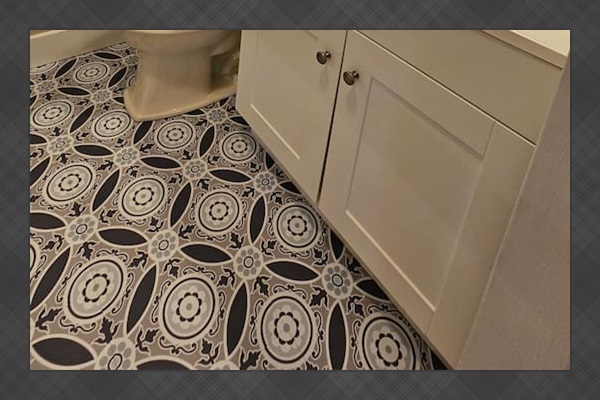 Charming bathroom with a sleek white vanity, bold patterned tile flooring, and a large round mirror for a fresh, modern feel.
