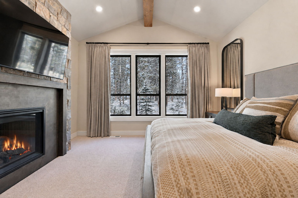 King suite with fireplace, TV and snowy forest views