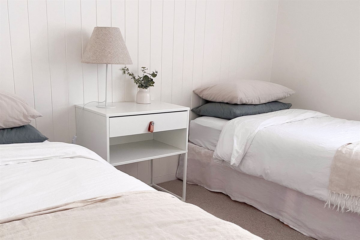This bedroom adds another comfortable sleep space, with layered bedding, bedside lighting and a simple uncluttered layout.