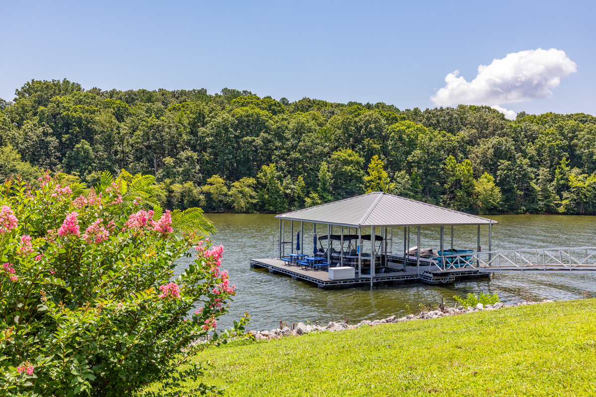 The View’s private covered dock sits just beyond the lawn, framed by summer flowers and calm Kentucky Lake water.