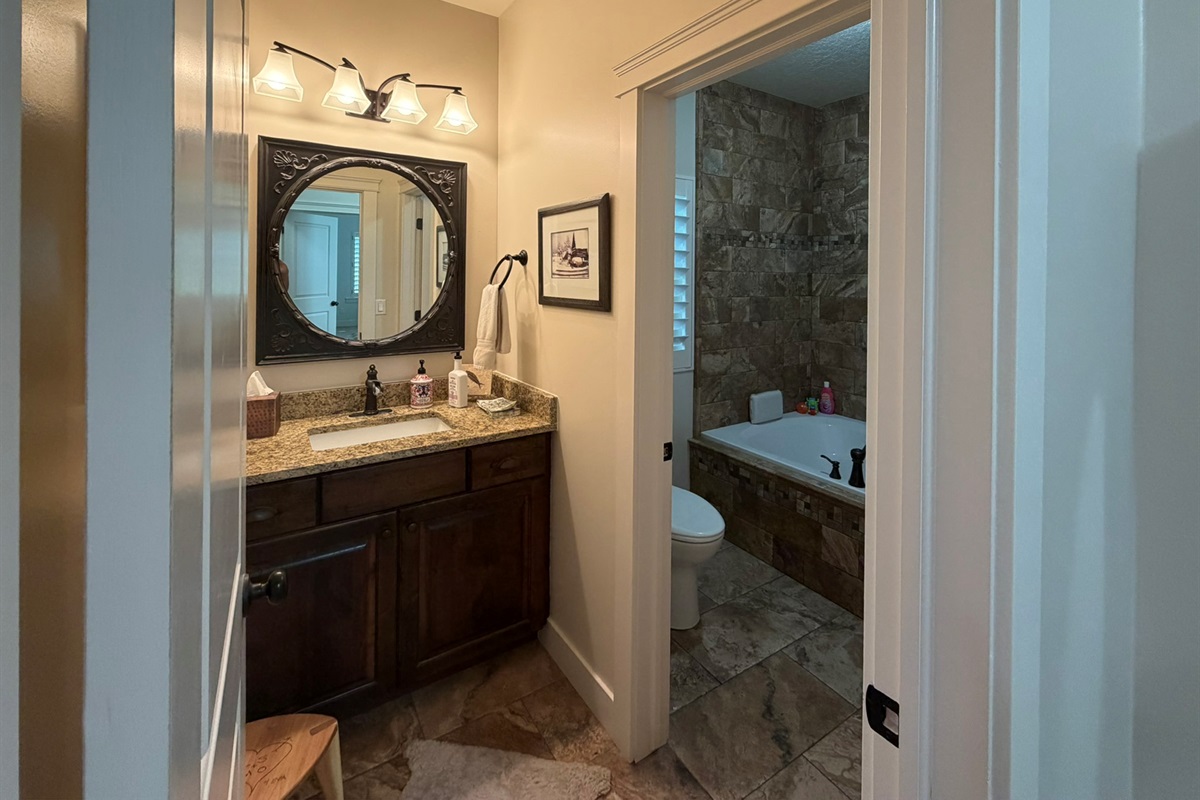 Convenient main-level guest bathroom with granite vanity and beautiful tile finishes located near the office/guest room.