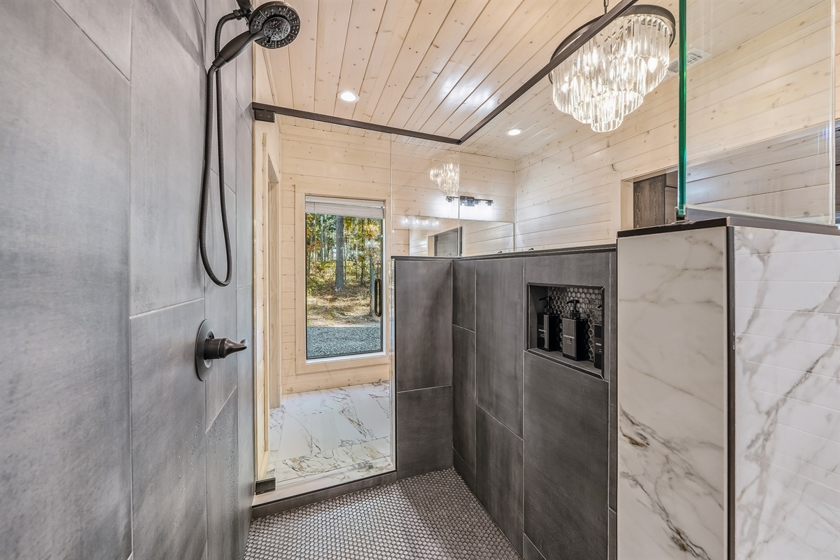 Walk in shower with dramatic tile, a rainfall head, and natural light pouring in from the picture windows.
