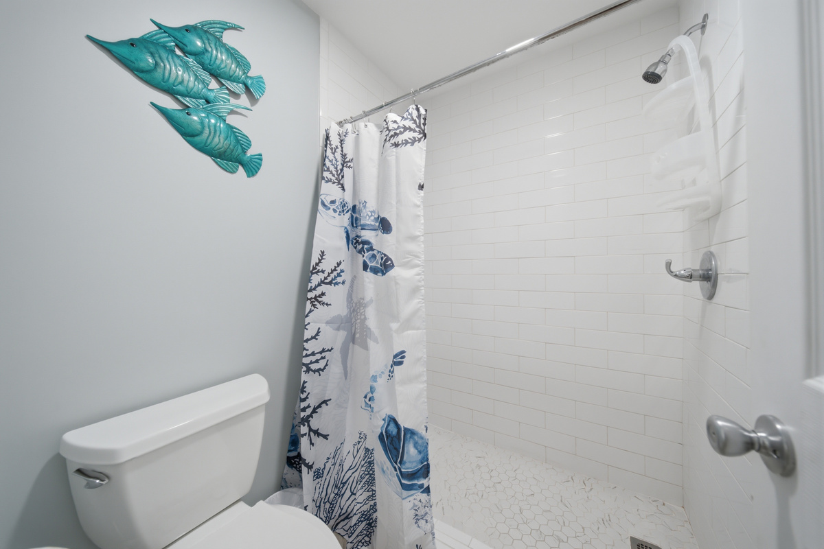 Second full bathroom with tiled shower and playful coastal decor