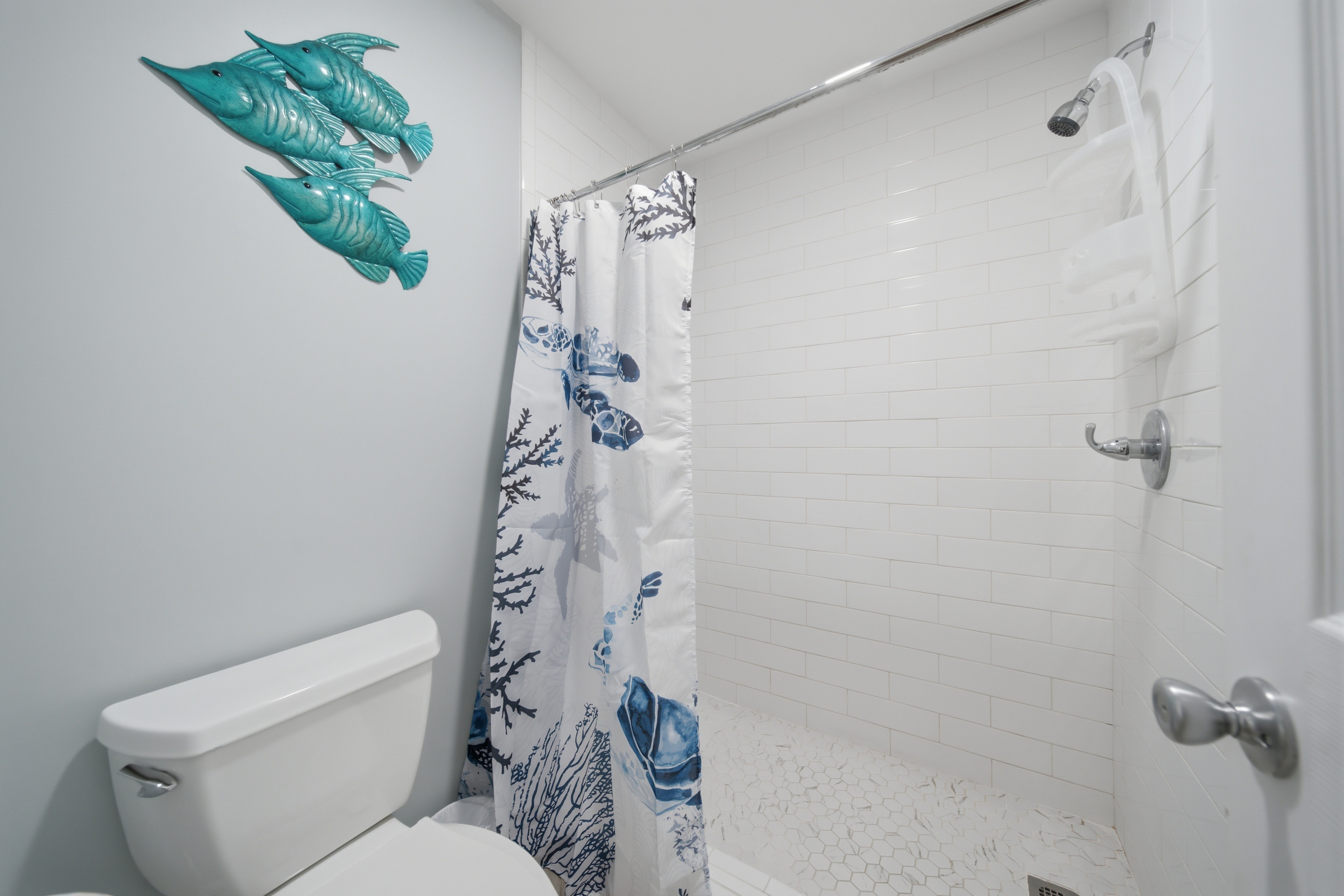 Second full bathroom with tiled shower and playful coastal decor