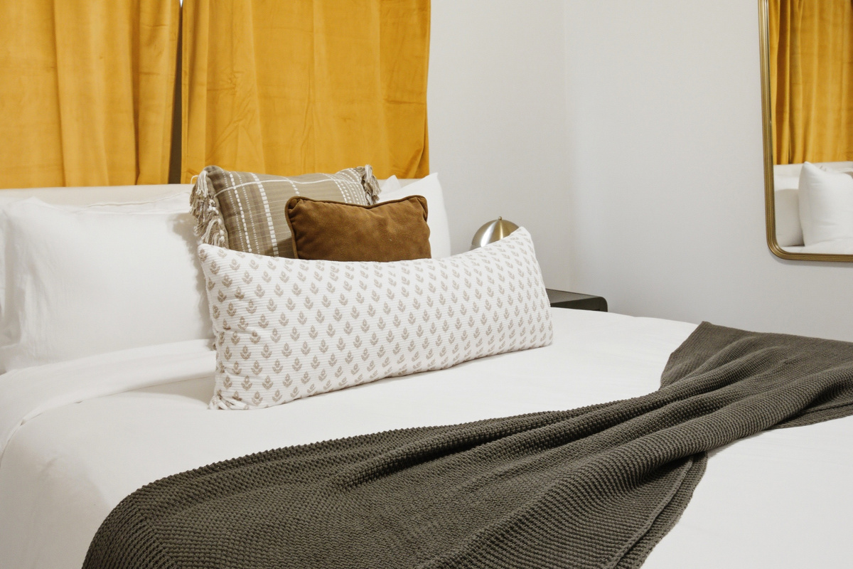 Queen Bed in Bedroom 3 with layered Bed Linens, Extra Pillows, and decorative throw. Cozy setup just a short drive from Six Flags and Hurricane Harbor.
