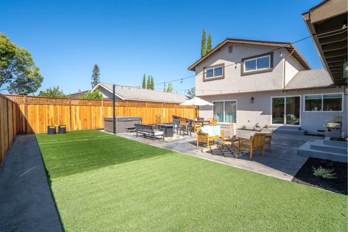 Backyard with hot tub, outdoor dining and seating with fire pit.