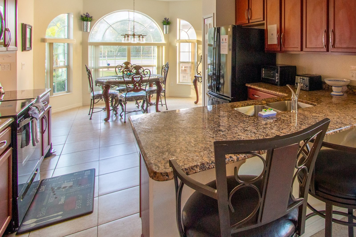 Fully stocked kitchen with granite countertops, stainless steel appliances, breakfast bar, and breakfast nook.